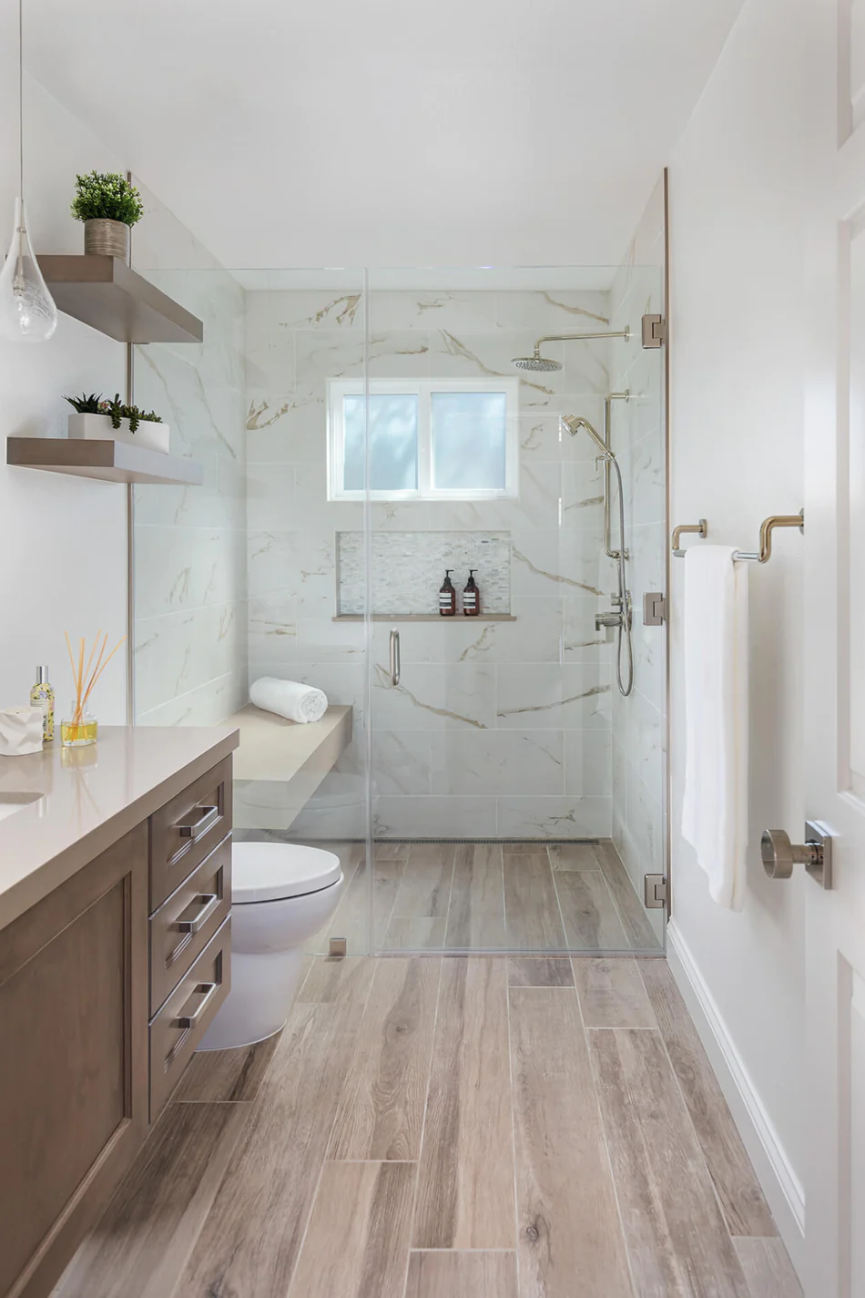 Completed bathroom remodel for Northeast Georgia homes with a glass walk-in shower, marble-look wall tiles, wooden vanity, and wood-look flooring