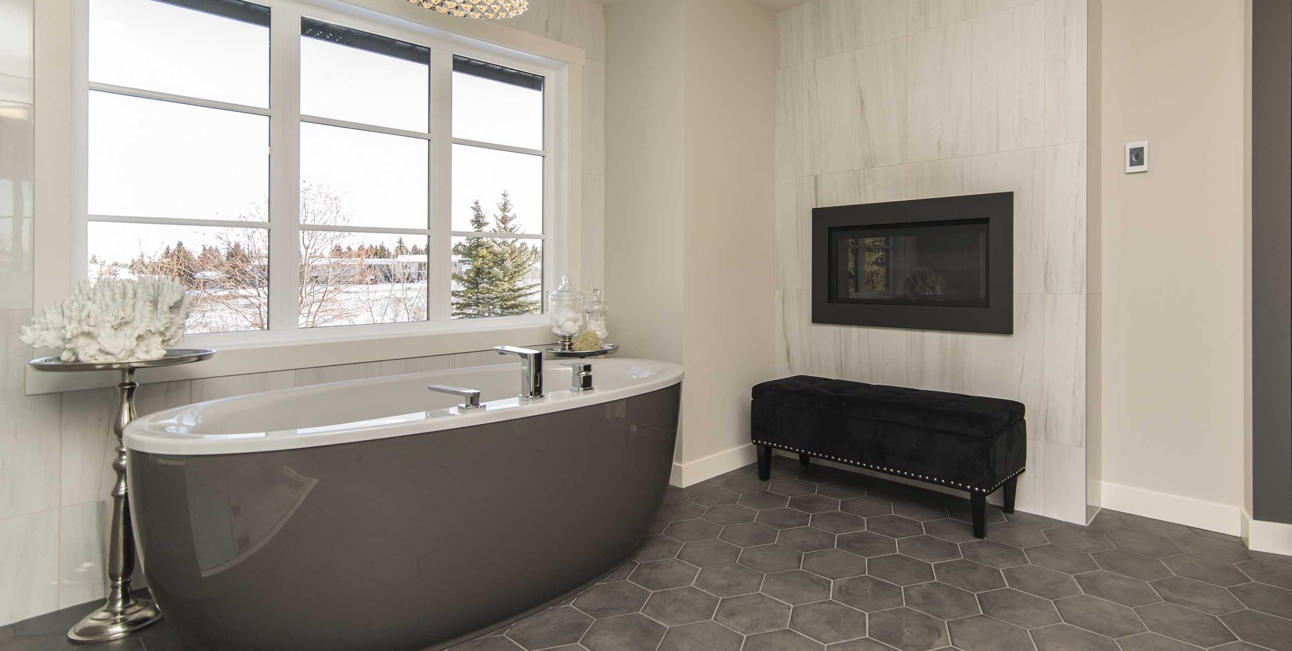 Luxury bathroom featuring a freestanding soaking tub, built-in wall fireplace, and dark hexagon tile flooring.