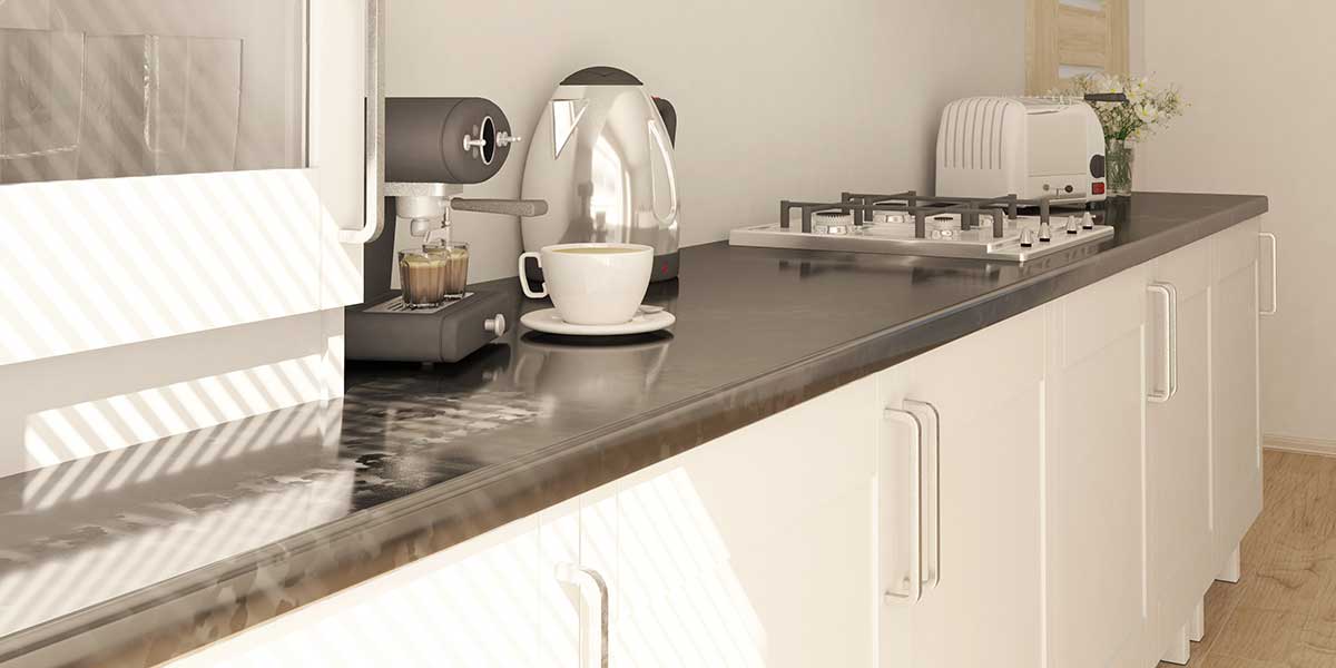 Close-up of a dark quartz kitchen countertop against white cabinetry with a coffee station on top.
